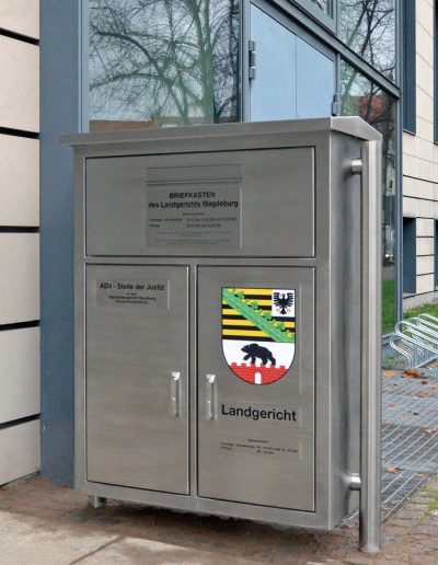 Breiter Briefkasten mit drei Türen, oben "Briefkasten des Landgerichts Magdeburg", links unten "ADV-Stelle der Justiz" und rechts unten "Landgericht"